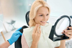 Patient using mirror to admire results of dental bonding procedure