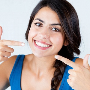 Happy woman with dental crowns pointing at her teeth