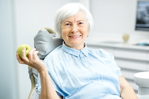 Senior woman enjoying apple with help of dentures