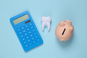 Piggy bank, calculator, and tooth arranged against blue background