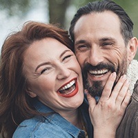 Man and woman smiling after repairing chipped tooth