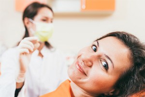 Patient smiling while dental team member holds extracted tooth