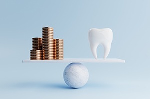 Tooth model balanced next to stack of coins