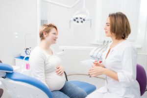 Woman speaking to dentist about getting dental implants during pregnancy in Watertown