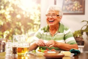 Senior woman enjoying a meal, eating with dentures in Watertown