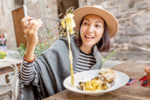 Woman smiling while enjoying a bowl of pasta