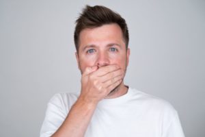 Man covering mouth after knocking out a tooth