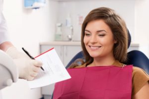 Smiling dental patient looking at paperwork